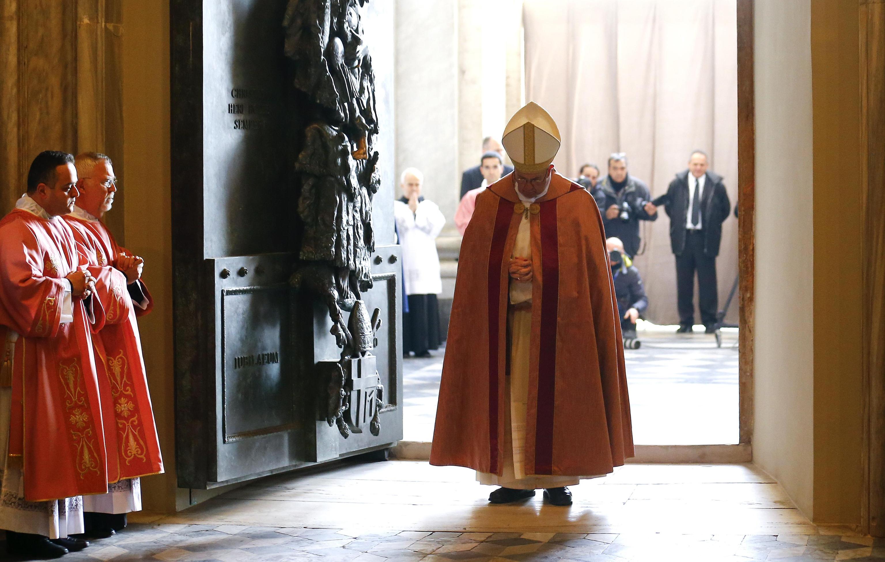 Pope Francis pauses and prays at the front of the Holy Door of the St John Lateran Basilica
